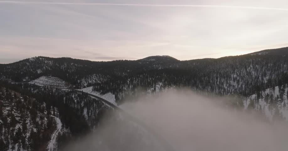 Panorama of a mountain range with coniferous trees and snow in the morning