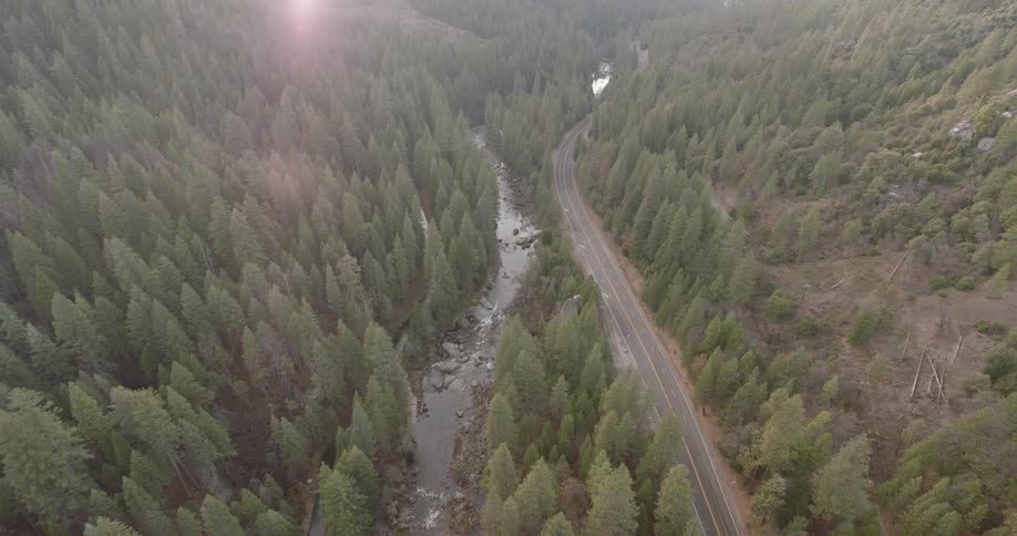 Aerial view of a road going alongside a river in the mountains
