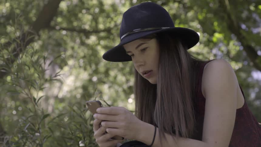 A woman is using her cell phone in a nature setting