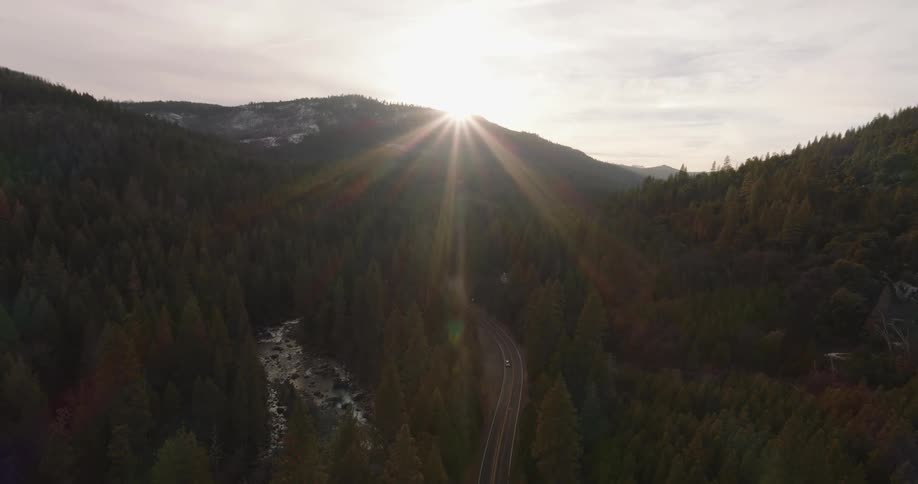Sunrisesunset over mountain peak vehicle drives on highway