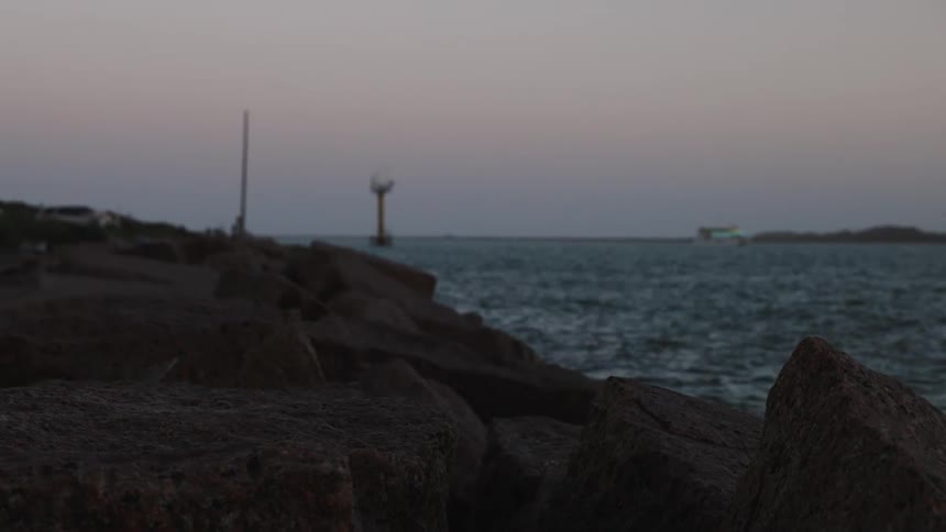 Seascape of rocks by the sea under a pink dawn sky
