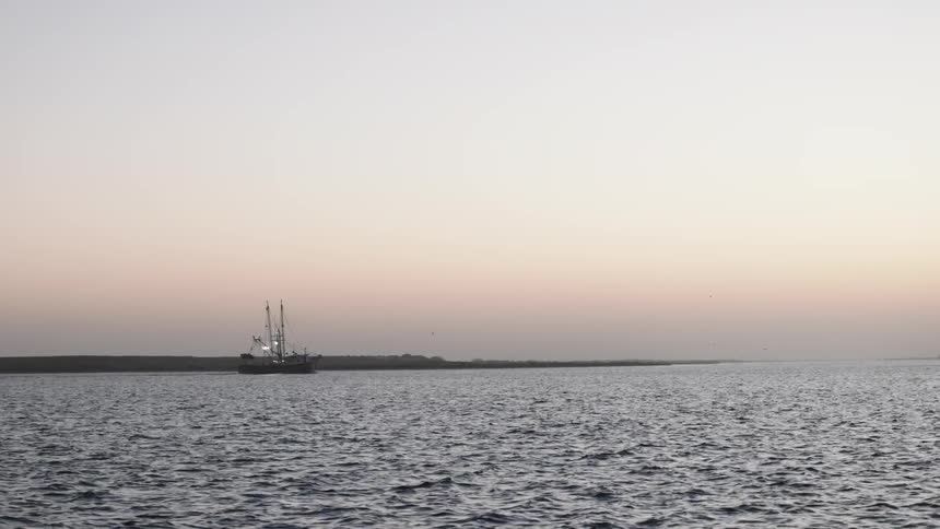 Panorama of a boat in the midst of the sea on a morning with a pink sky