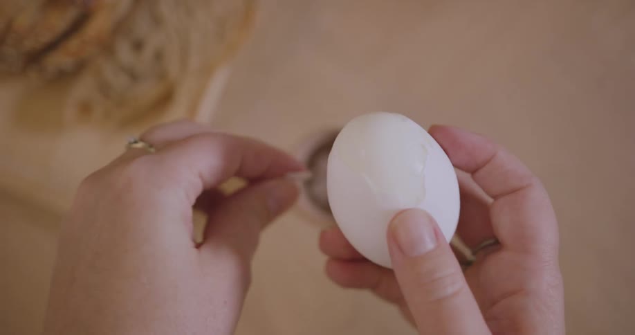 A person removing the shell from a boiled egg