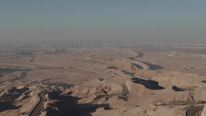 Aerial view of a winding highway in the desert cutting through the vast expanse of arid landscapes