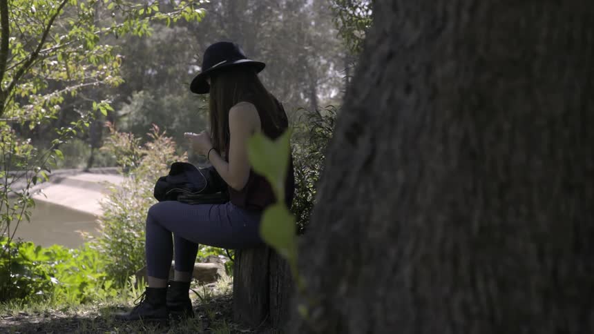 A woman uses her phone in a forested area