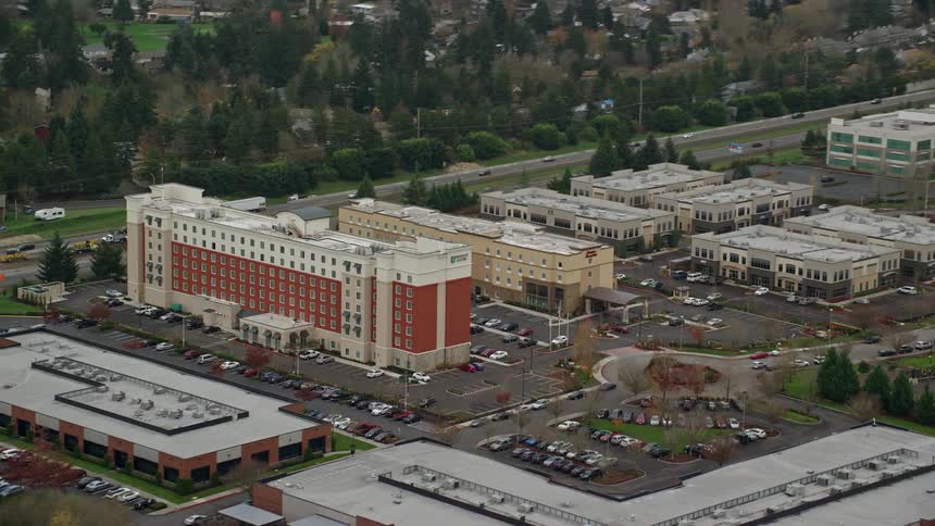 Aerial panorama of buildings and commercial establishments next to the highway amidst trees
