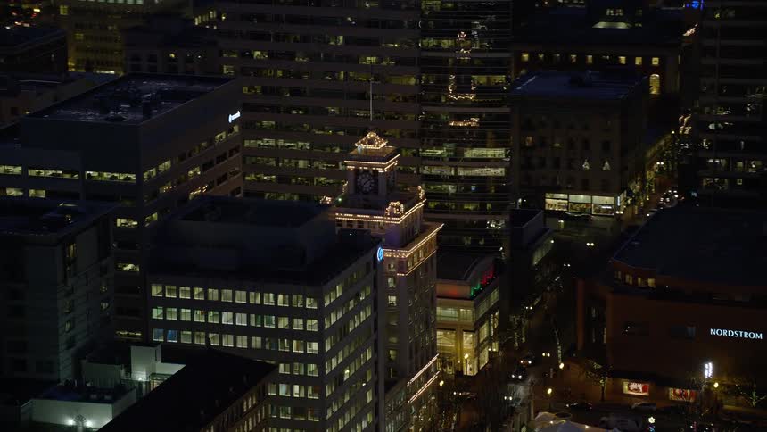 Lights on metropolitan buildings and towers glow in the darkness as traffic moves on the streets