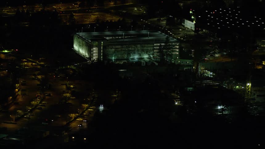Aerial view of a building surrounded by construction cranes at night