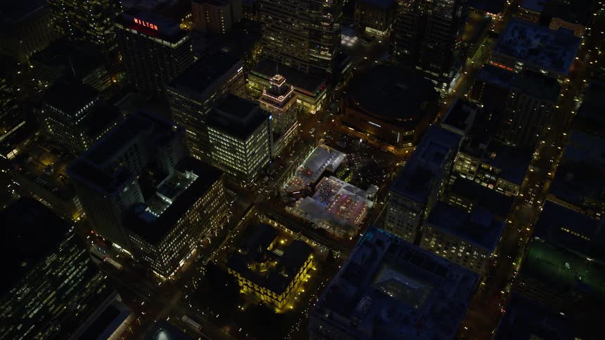 Lights on metropolitan buildings and towers glow in the darkness as traffic moves on the streets