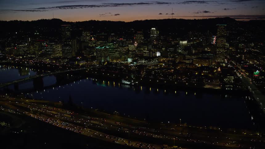 Aerial panorama of a metropolis with nighttime skyscrapers by the sea and a purple evening sky