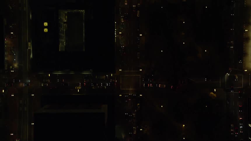 Aerial panorama of a nighttime metropolis overlooking an intersection with vehicles traffic