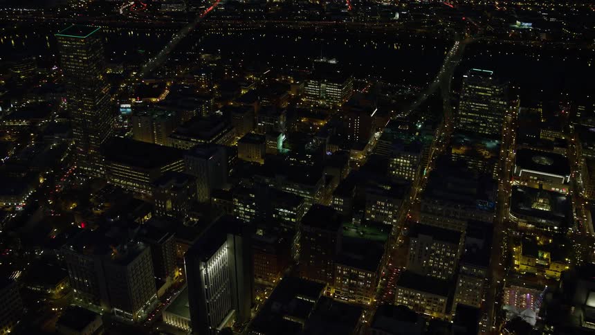 Aerial flyover at night of metropolis downtown skyline dotted with yellow light