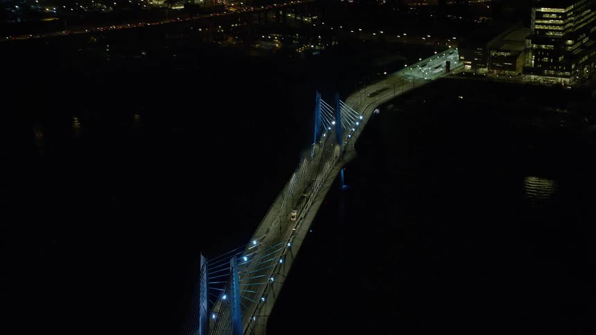 Aerial view of a bridge over a river next to a city at night