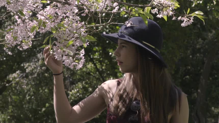 A woman touches the flowering branches of a tree