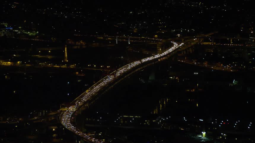 Slowly moving cars on a city bridge at night