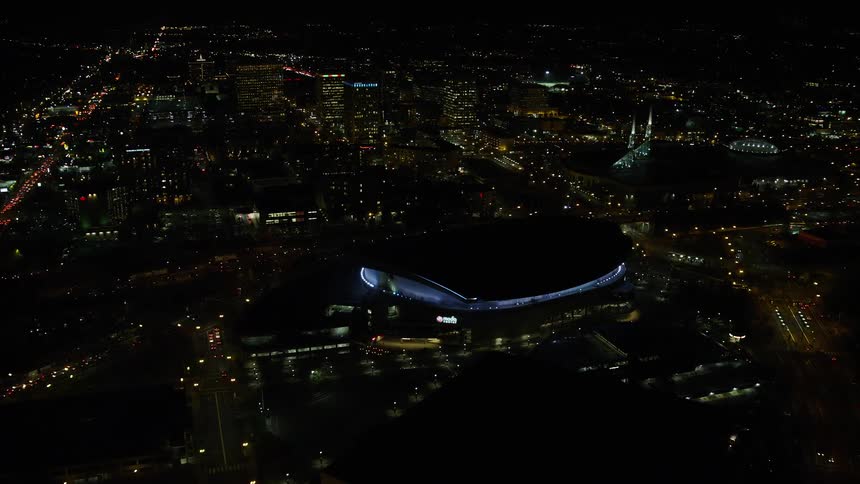 Aerial view of illuminated buildings and a stadium in the city at night