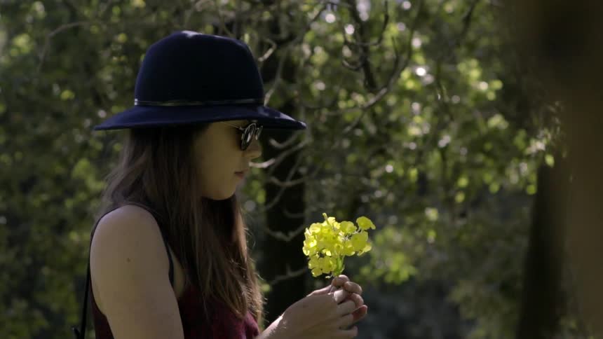 A woman looks at some yellow flowers in her hands