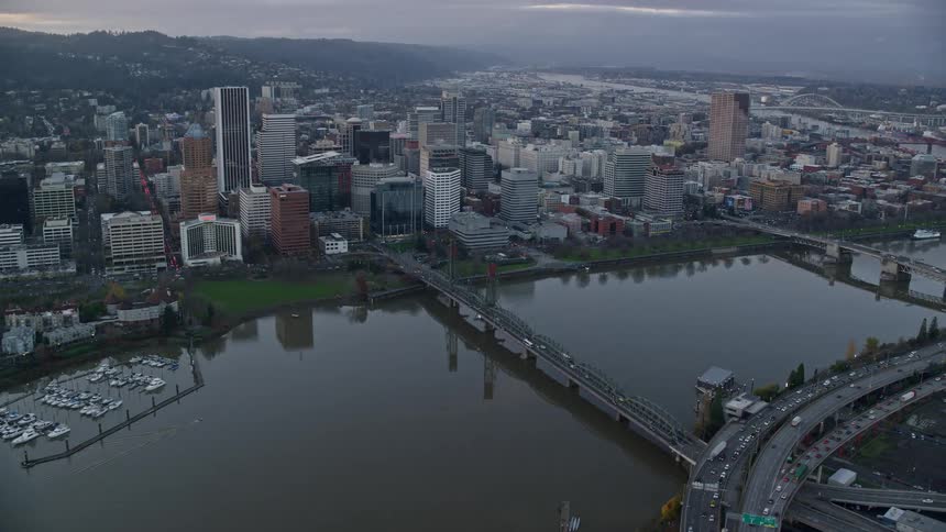An aerial view captures bridges spanning over a river surrounded by waterfront buildings in the cityscape
