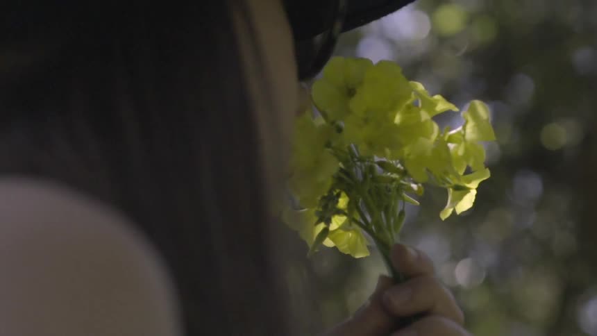 A woman smells a small bunch of yellow flowers