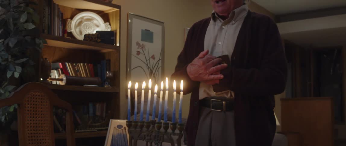 A man singing in front of candles while holding a book in his living room