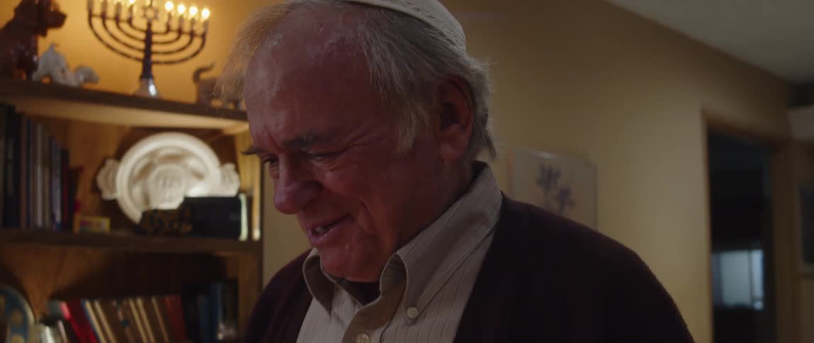 A man talks next to hanukkah candles