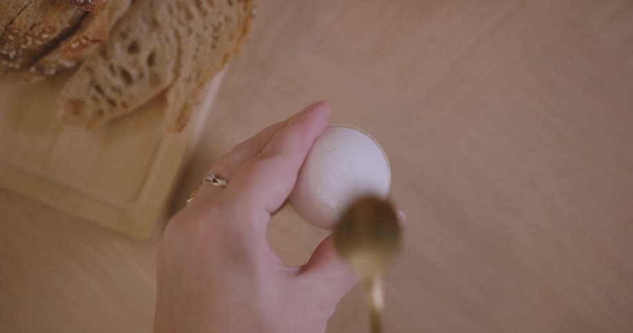 A person begins peeling a hardboiled egg