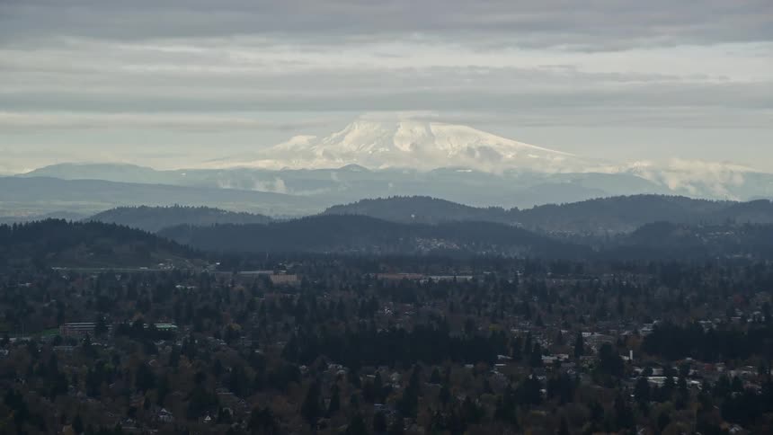 Panoramic of rural houses scattered in forest covered foothills with a thin hazy sky and mt hood in the background