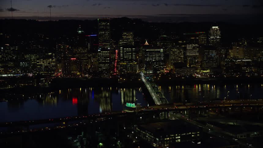 Skyline of an urban city with illuminated buildings and vehicles crossing the bridge