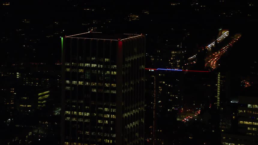 Skyline of a building with shiny mirrored windows at night in the city
