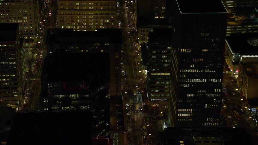 Aerial of city skyline at night with yellow lights dotting black silhouetted buildings downtown