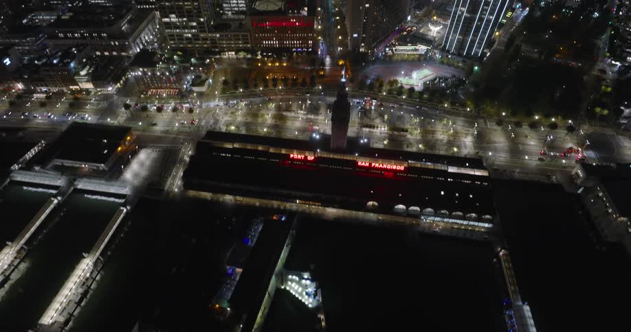 Wispy clouds float over brightly lit downtown skyscrapers near waterfront