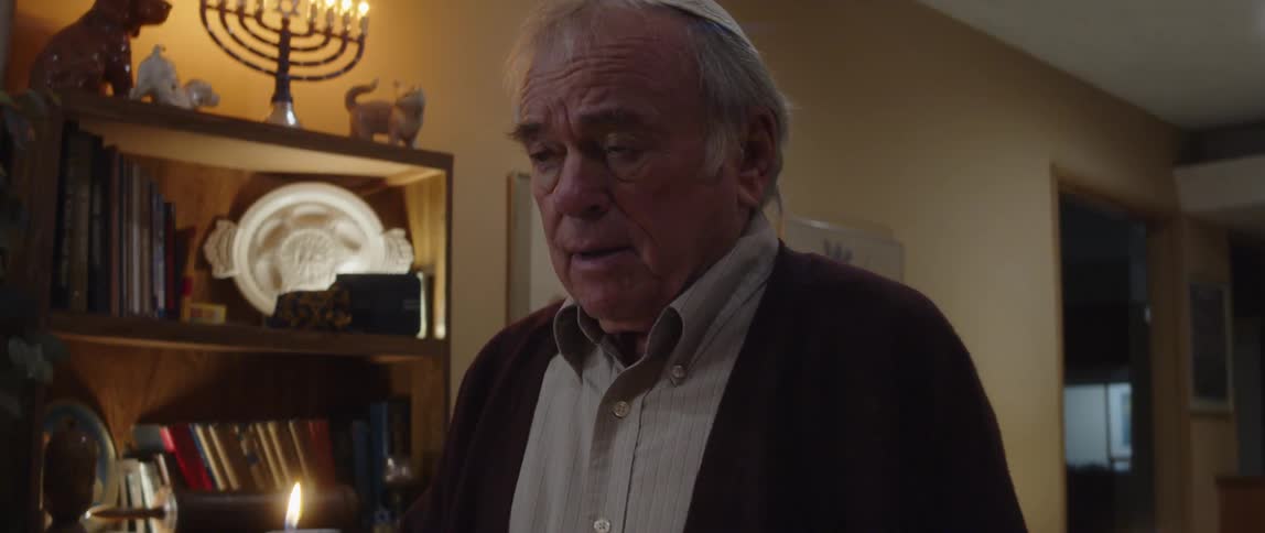 Portrait of an elderly person lighting a candle with a facial expression of emotion