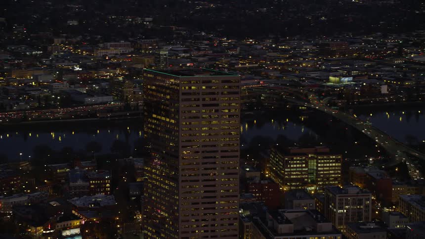 Aerial view of illuminated tall buildings along the riverfront in the city in the evening