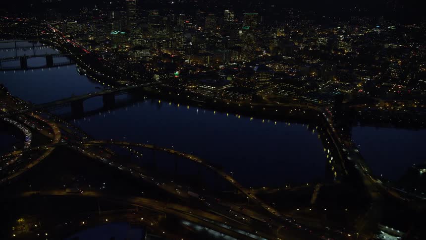 Aerial panorama of a nighttime metropolis with skyscrapers bridges over lakes and traffic of vehicles under the streets