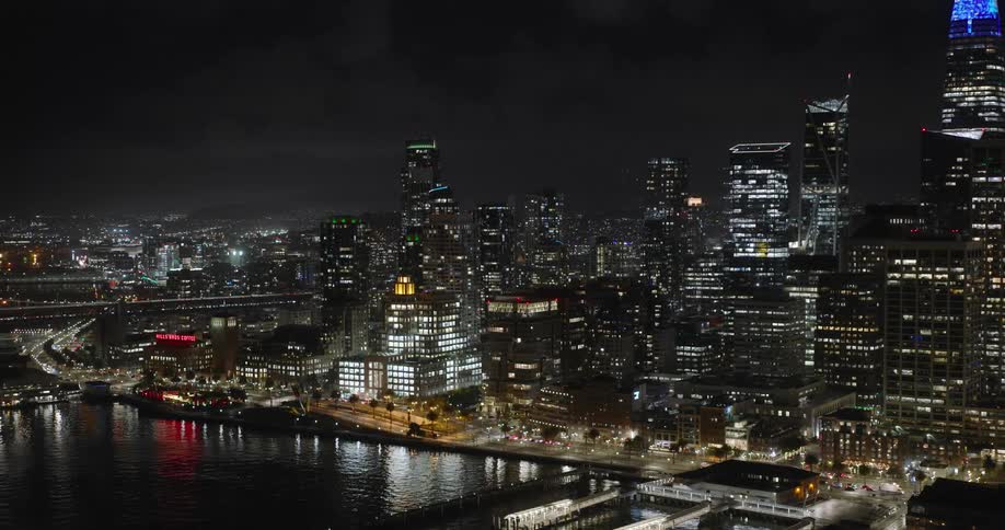 Aerial panorama of a nighttime metropolis by the seaside with skyscrapers