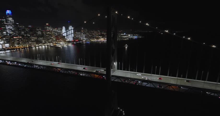 Traffic over a suspension bridge next to the city at night