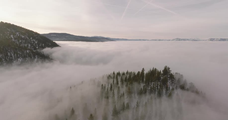 Thick fog blankets the base of snowy mountains