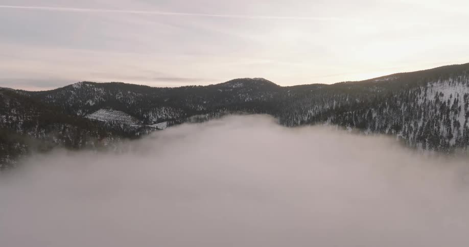 Mountains covered in snow behind a river of thick fog