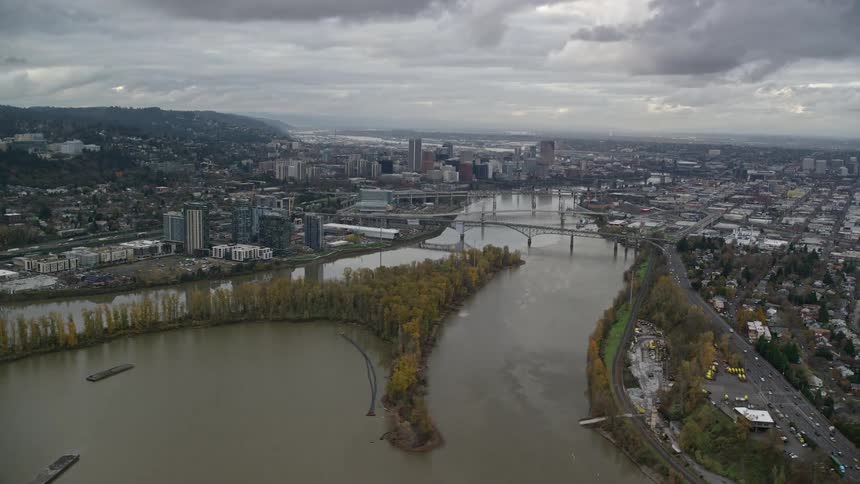 Aerial panorama of a metropolis by a lake with a mountain range on the horizon on a cloudy day