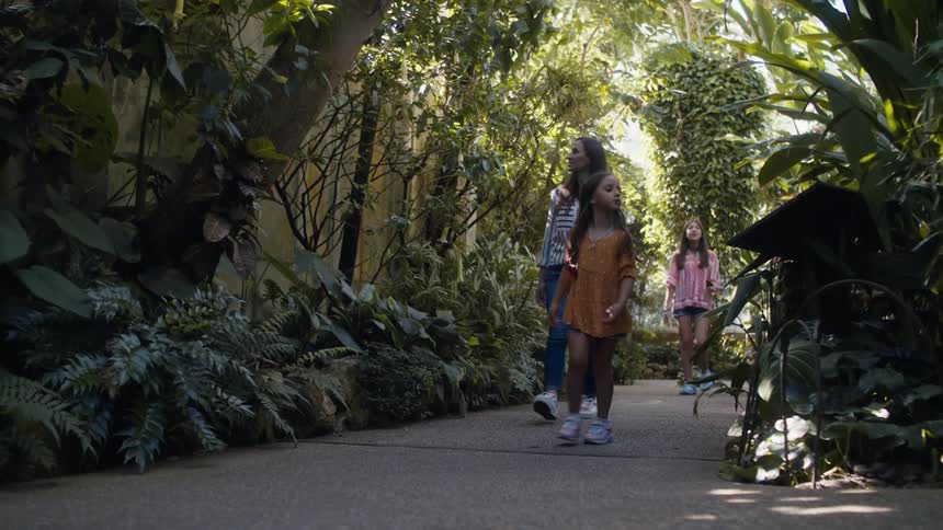 Mother walking with her two daughters in a garden