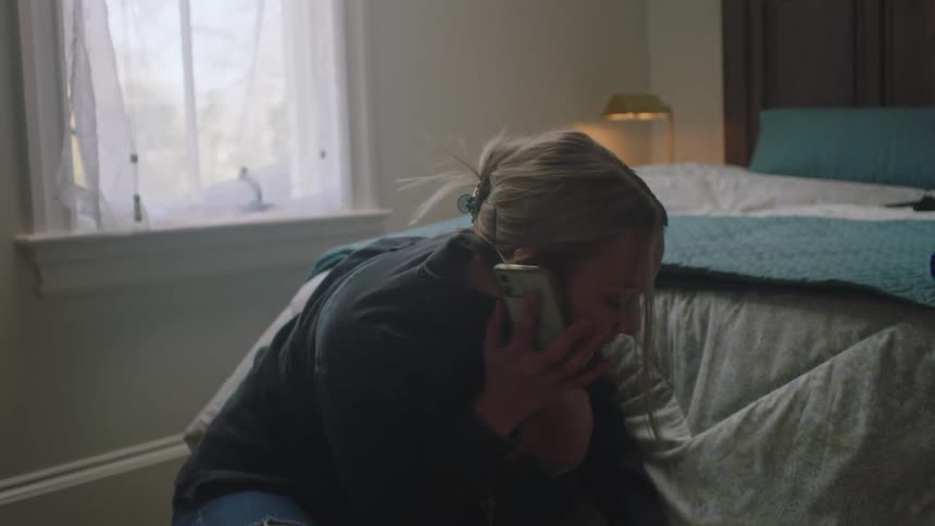 A woman is talking on the phone as she picks up a cassette tape