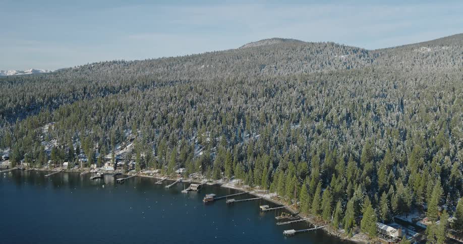 Panorama of mountains covered with conifers and snow by the sea with docks