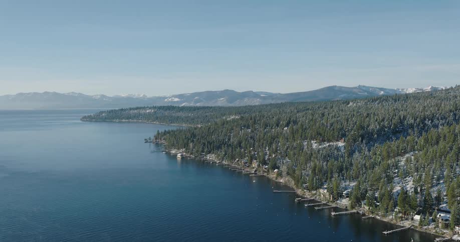 Aerial of marina on mountainous coast with snow covered forest