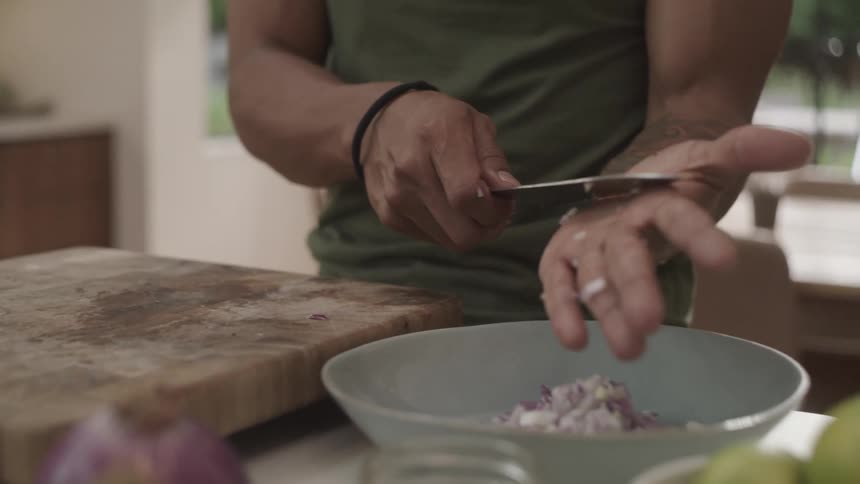 A clip of a man moving onion from a chop board to a bowl