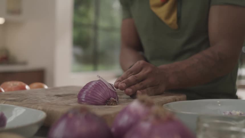 A person in th kitchen cutting onion with a knife