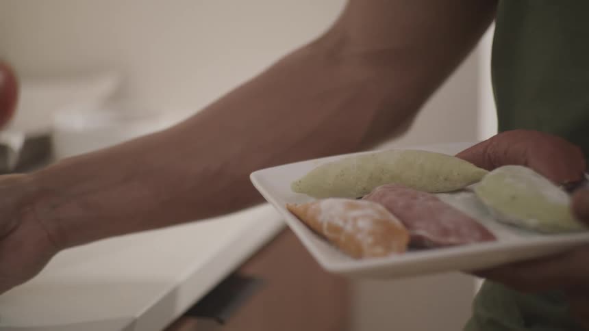 A person holding a plate with various colored dough