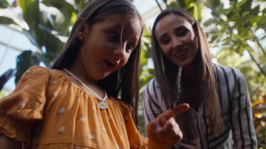 An excited girl with a butterfly on her finger in the tropical forest
