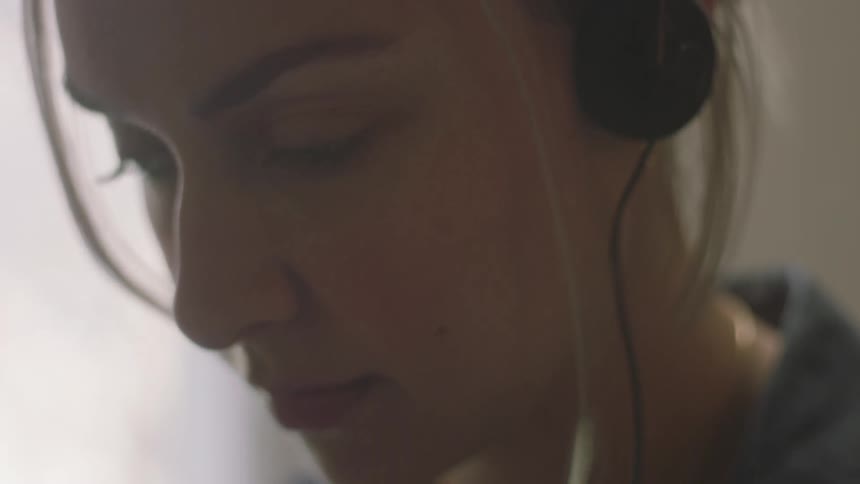 Blonde girl wearing a denim jacket wears headphones
