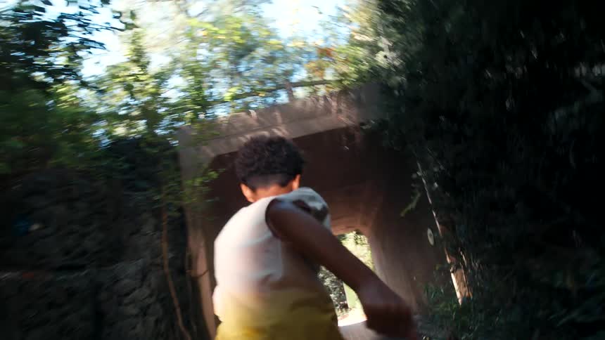 Boy runs toward and through tunnel under road on a sunny day