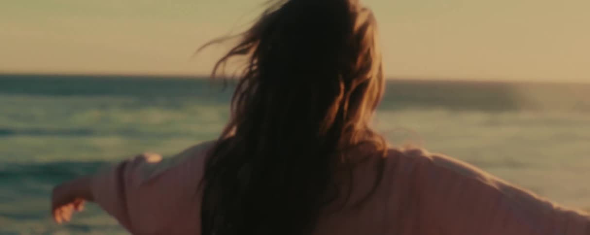 Happy young woman dances on the beach